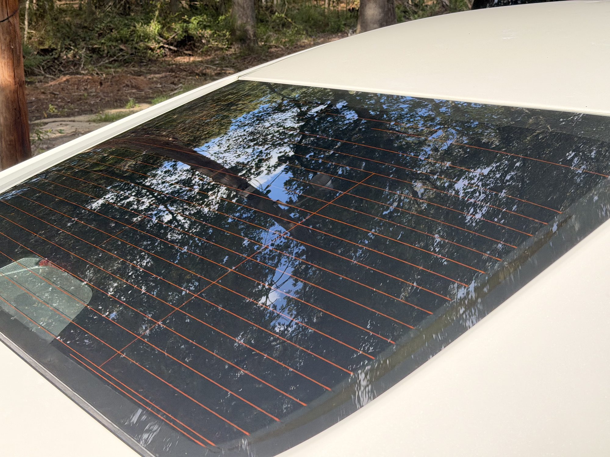 Close-up of ceramic tint film on a rear windshield with defrost lines visible