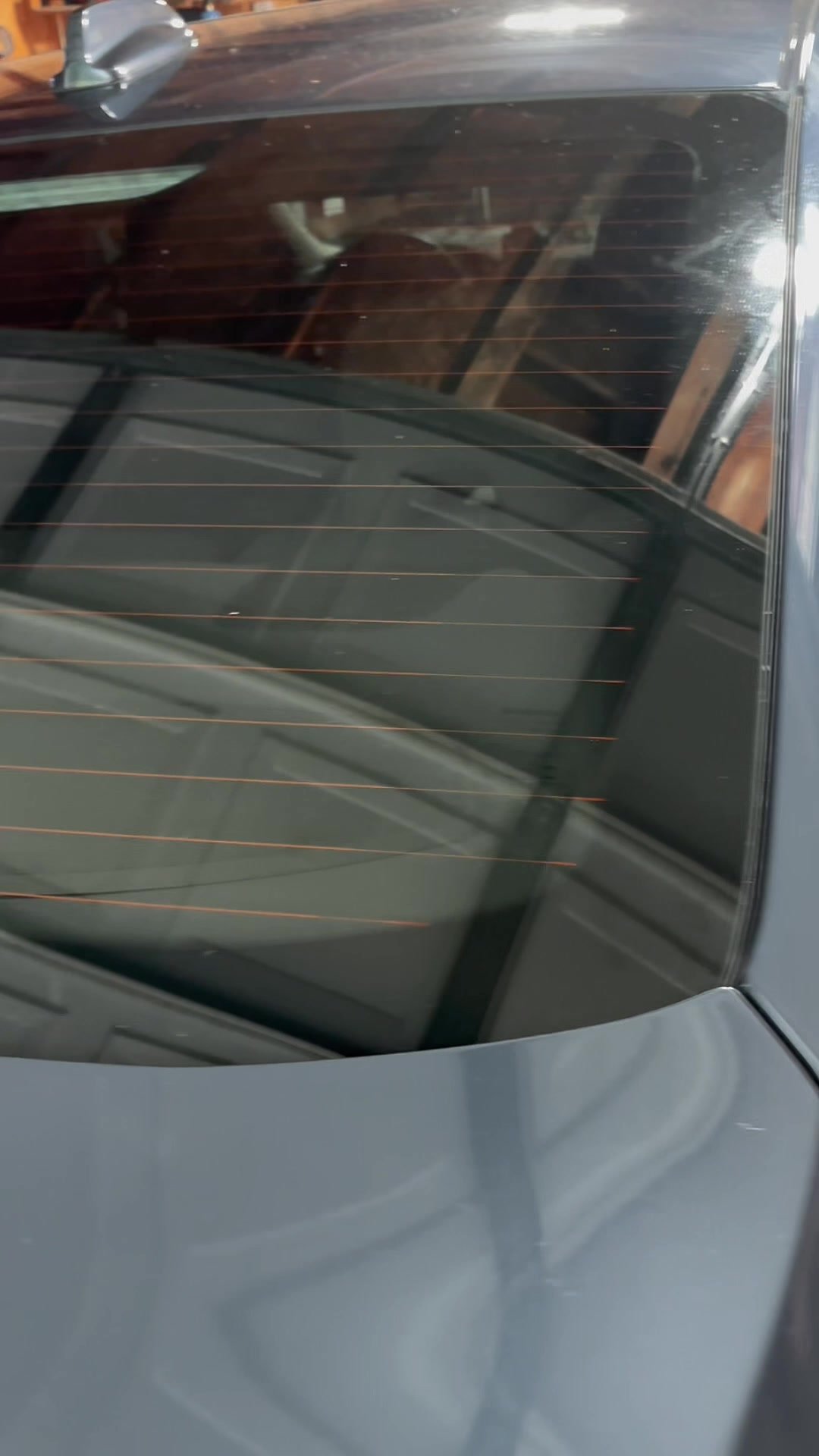 Rear windshield mid-installation, showing ceramic tint film applied to the upper half and untinted glass on the lower half